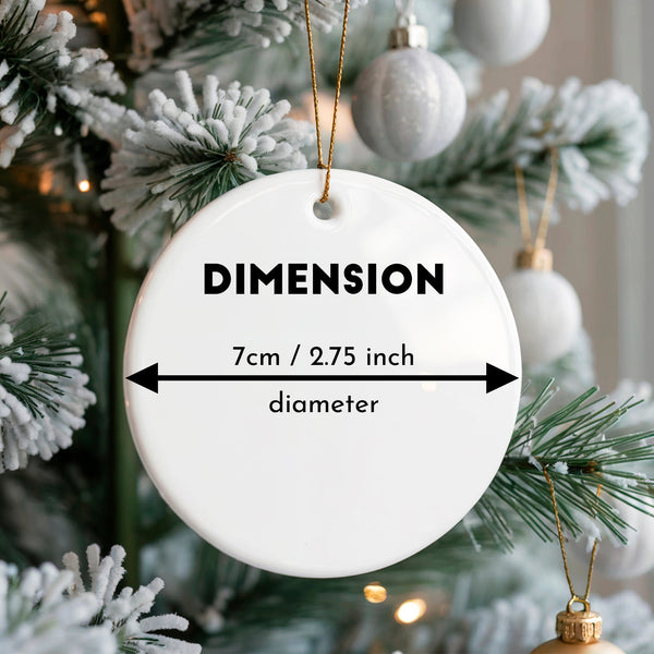 White ornament with dimensions labeled hanging on a Christmas tree.