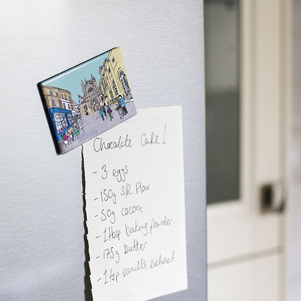 Shopping list held in place by a fridge magnet with an illustration of Bath Abbey